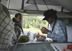 Men are eating in rental campervan