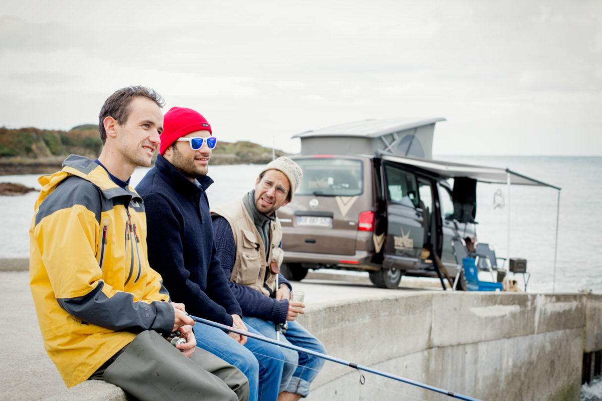 Hommes pêchant près d'un fourgon aménagé