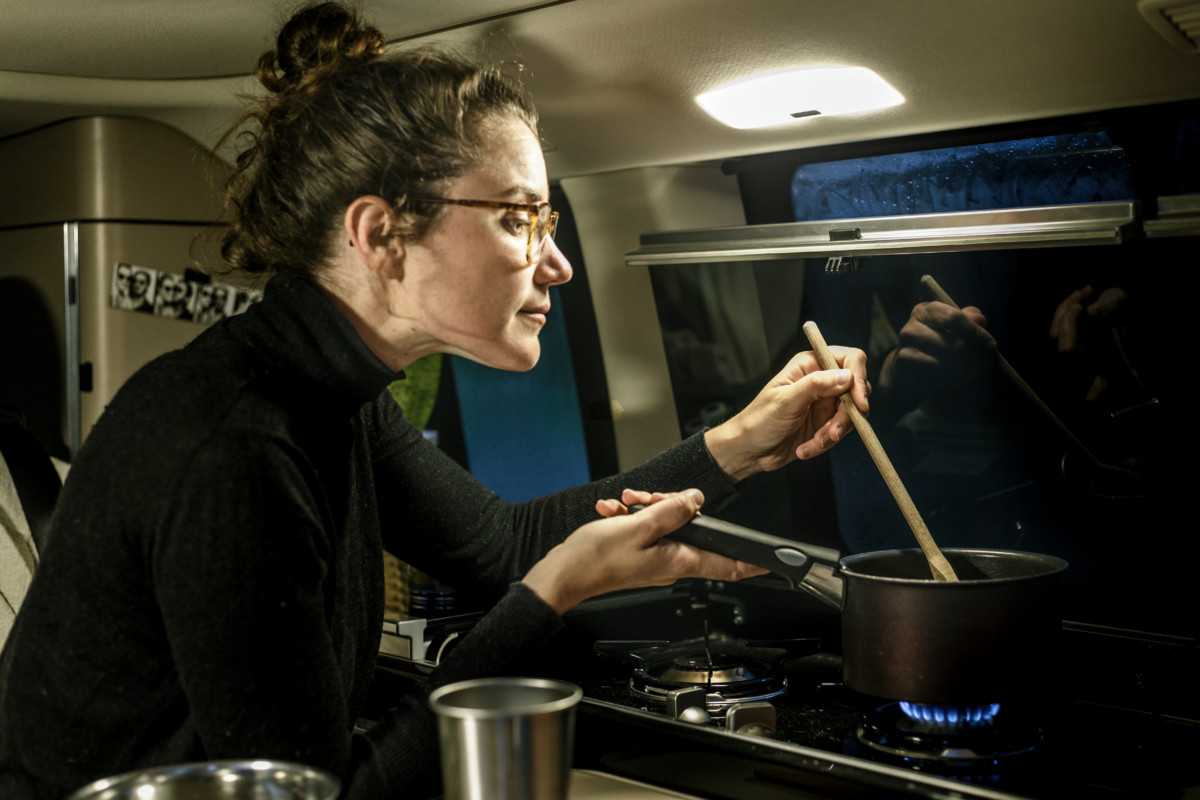 Femme cuisinant à l'intérieur d'un van aménagé