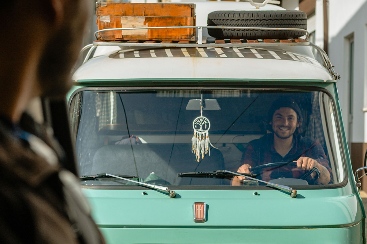 Homme souriant à l'intérieur d'un van aménagé 