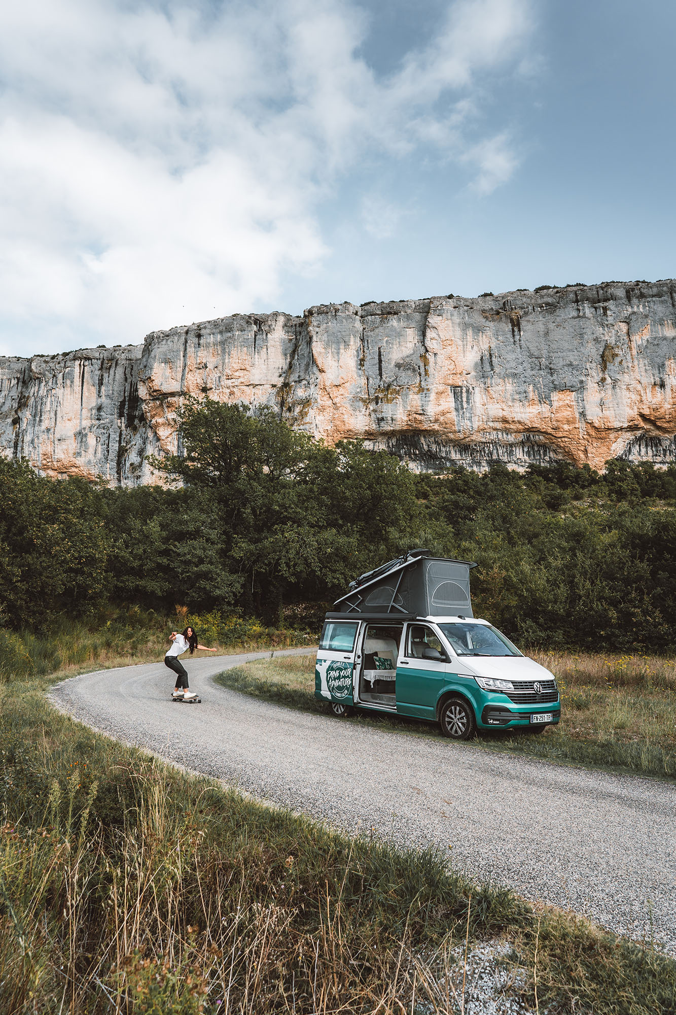 Femme faisant du skate près d'un campervan